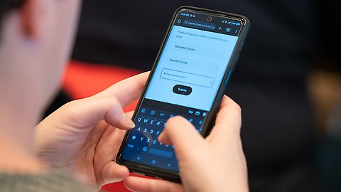 Ein Handy wird in beiden Händen gehlaten, die Daumen tippen auf das beleuchtete Display. Ein Handy wird in beiden Händen gehlaten, die Daumen tippen auf das beleuchtete Display.